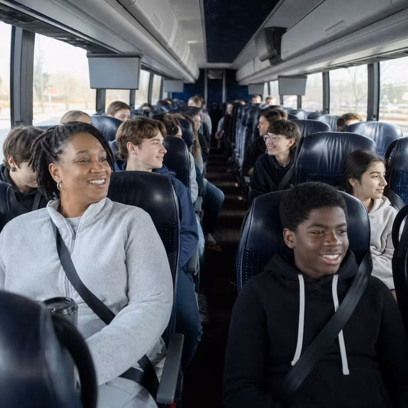 Group boarding a white charter bus for School Transportation transportation in Arlington